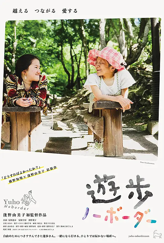 安積遊步坐在輪椅上與年輕介助者交流，神情堅定平靜